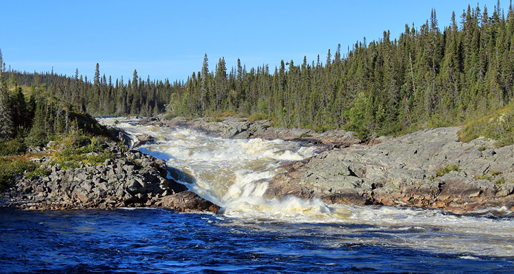 The Magpie River tumbling over brief rapids on a bright day.