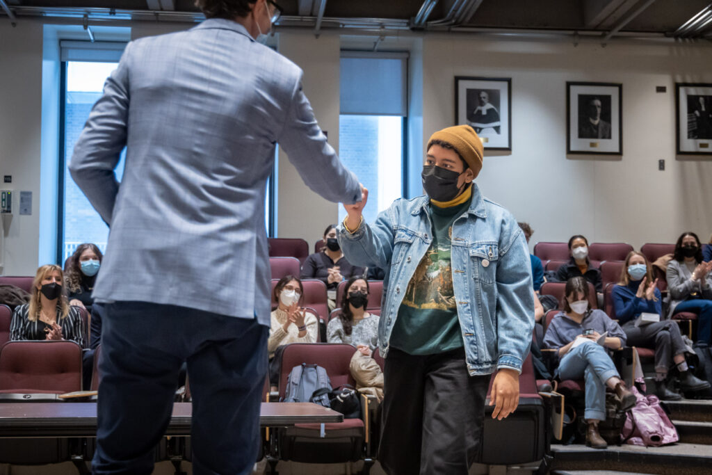 A student wearing a beanie and a jean jacket receives their civil code